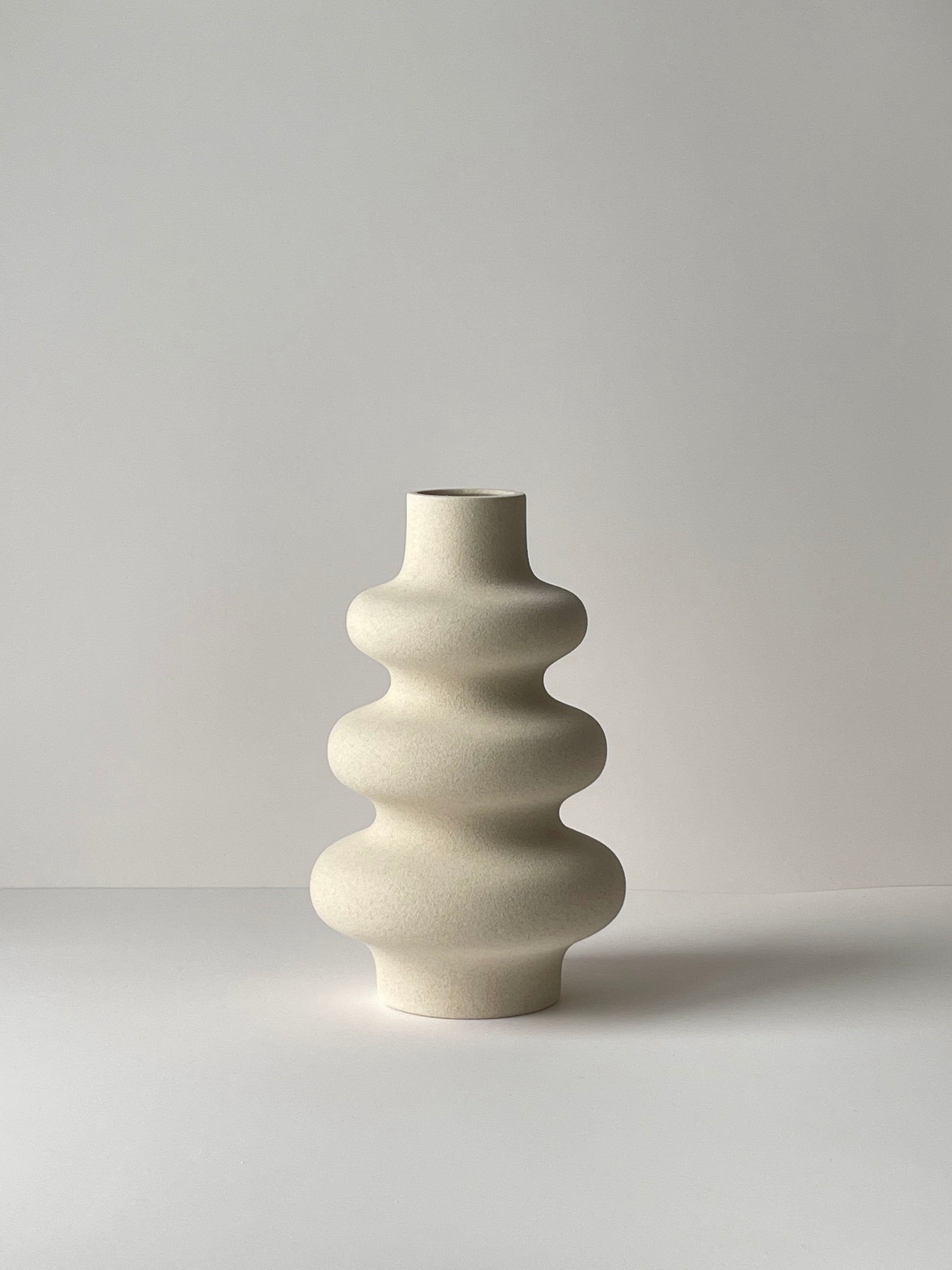 White ceramic vase with a textured design on a light gray background